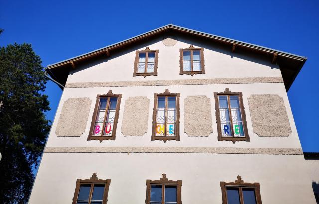 Foto einer Hausfassade mit dem Schriftzug BÜCHEREI in den Fenstern der ersten Etage.