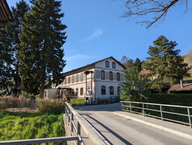 Foto vom Haus im Grünen mit der Zugangsbrücke im Vordergrund.