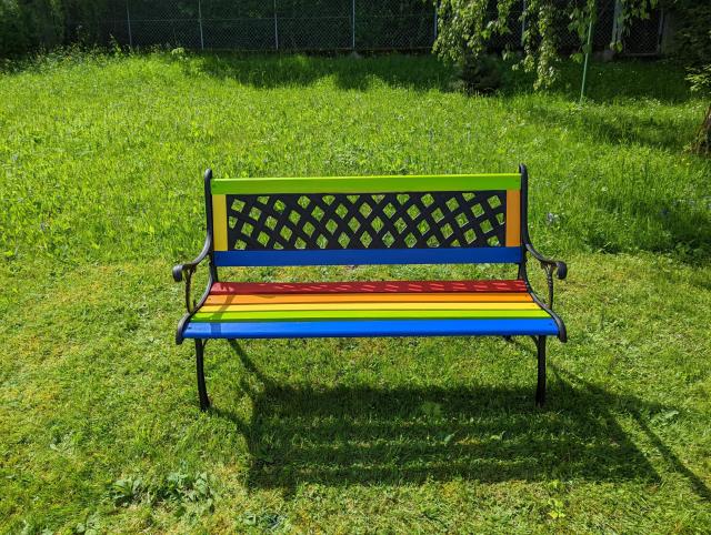 Foto der Regenbogenbank der Bücherei auf einer Wiese.